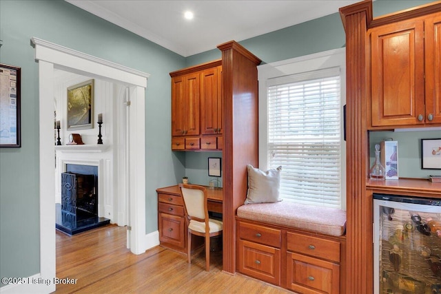 office area featuring bar area, beverage cooler, built in desk, and light hardwood / wood-style floors