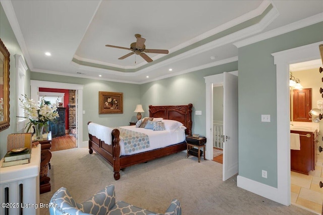 bedroom with crown molding, ceiling fan, ensuite bath, and a tray ceiling