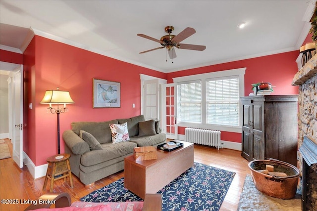 living room featuring radiator, ornamental molding, and light wood-type flooring