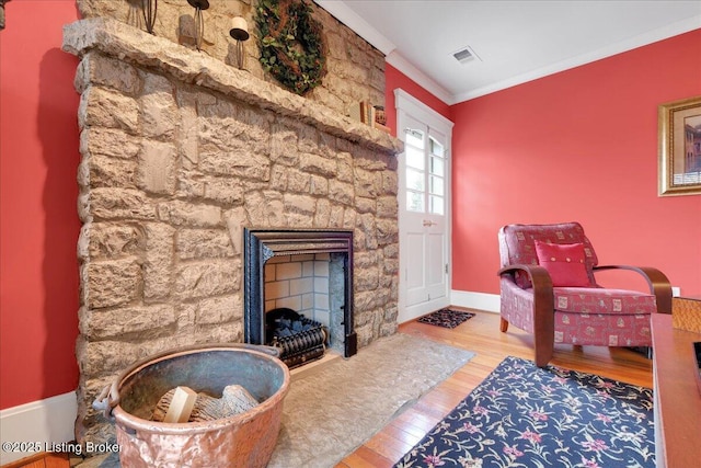 sitting room featuring crown molding, a stone fireplace, and hardwood / wood-style floors