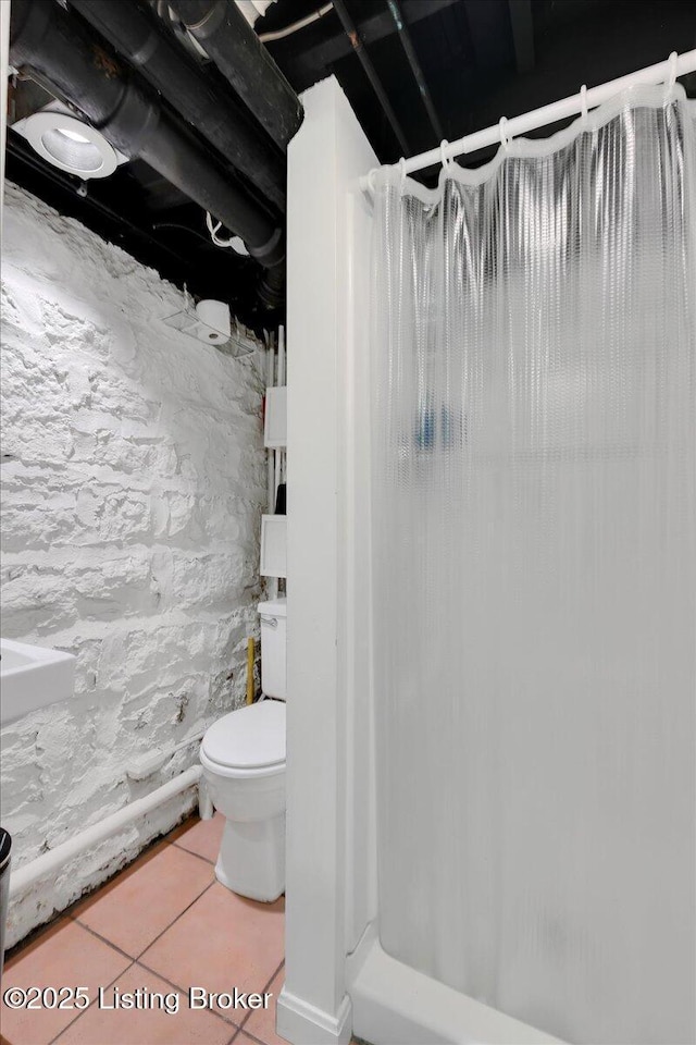 bathroom featuring a shower, tile patterned floors, and toilet