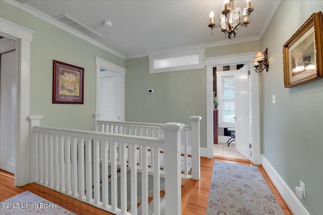 hall with crown molding, a notable chandelier, and light hardwood / wood-style flooring