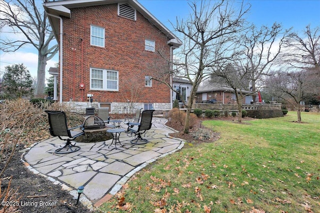 rear view of property featuring a patio, a yard, and an outdoor fire pit