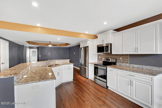 kitchen featuring stainless steel appliances, a spacious island, white cabinets, dark wood-style floors, and tasteful backsplash