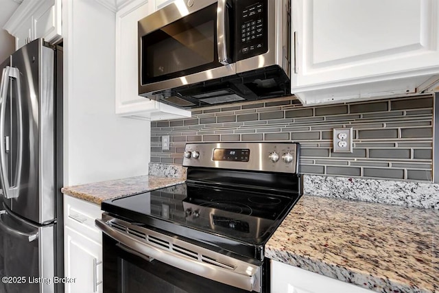 kitchen featuring light stone counters, appliances with stainless steel finishes, white cabinets, and backsplash