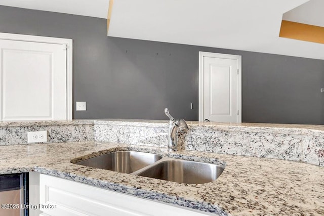 details with a sink, light stone countertops, and white cabinets