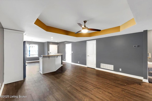 kitchen with dark wood-style floors, a raised ceiling, visible vents, freestanding refrigerator, and baseboards