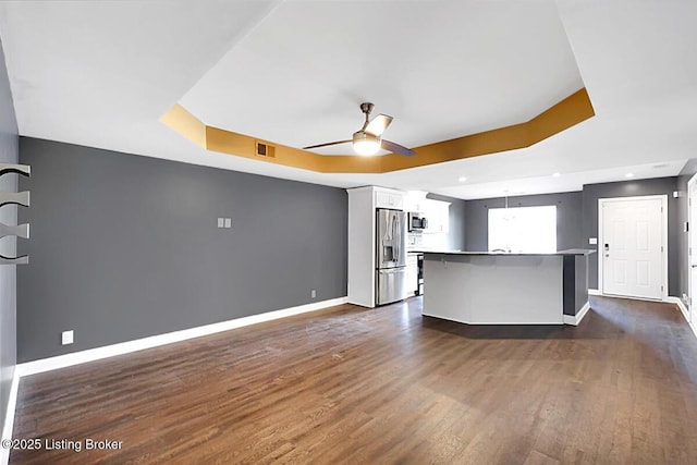 kitchen featuring baseboards, visible vents, a raised ceiling, a ceiling fan, and stainless steel appliances