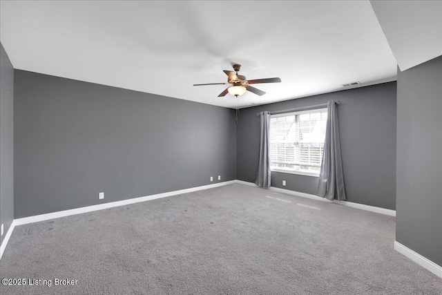 carpeted spare room with a ceiling fan, visible vents, and baseboards