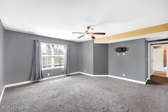 spare room featuring carpet flooring, ceiling fan, visible vents, and baseboards