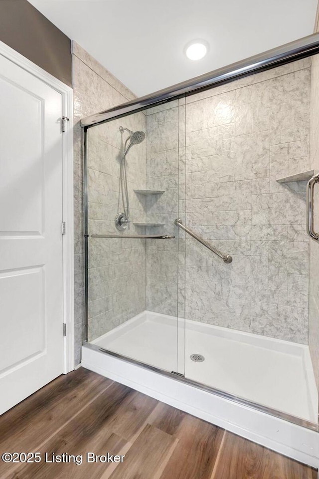 full bath featuring a shower stall and wood finished floors