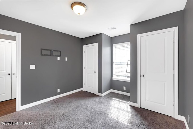 unfurnished bedroom featuring dark carpet, visible vents, and baseboards