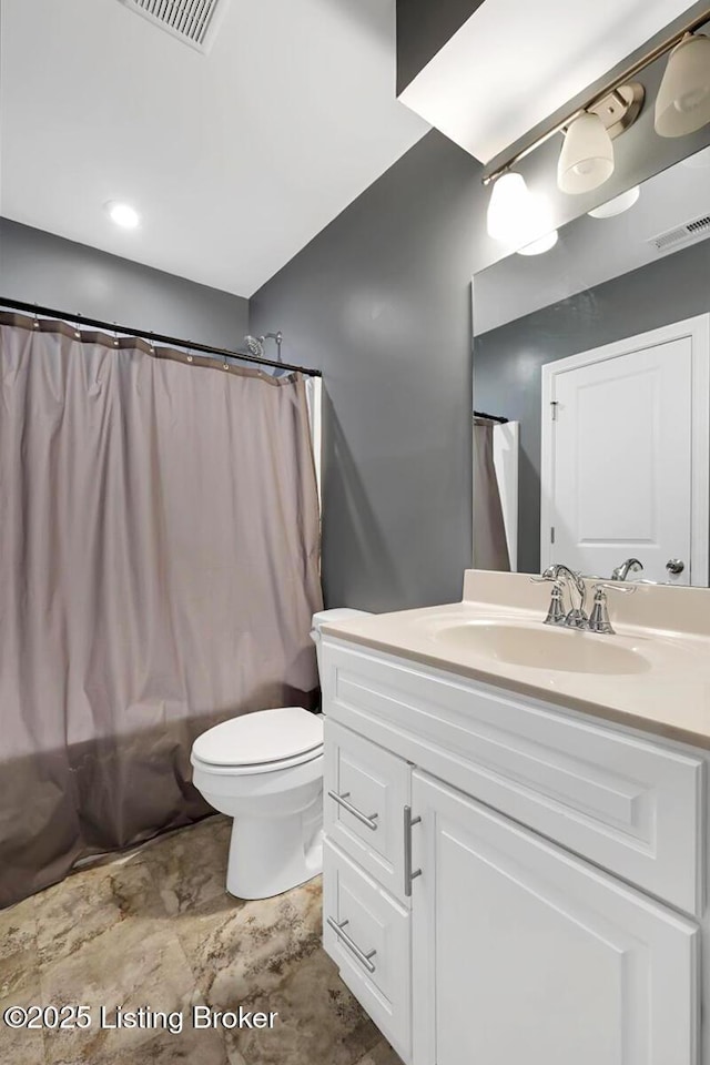 bathroom featuring toilet, vanity, and visible vents