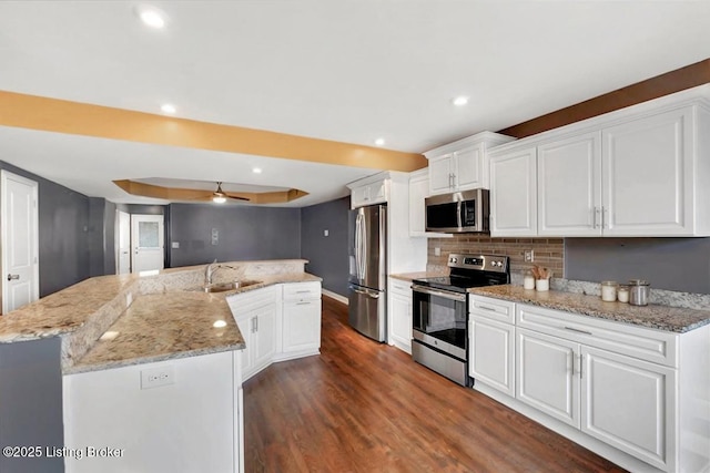 kitchen with dark wood-style flooring, a large island, decorative backsplash, appliances with stainless steel finishes, and white cabinetry