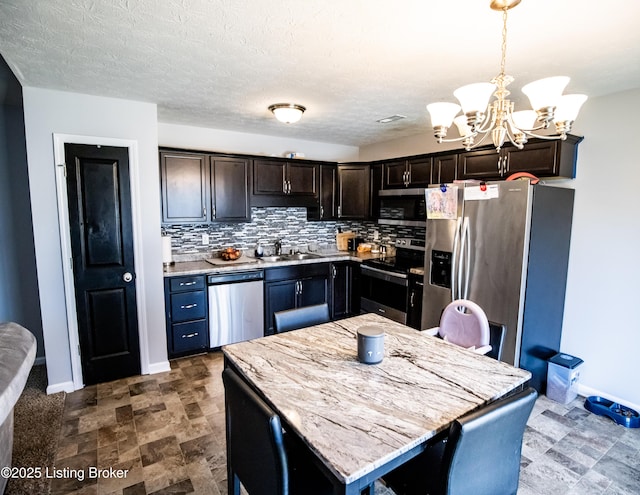 kitchen with appliances with stainless steel finishes, a kitchen island, tasteful backsplash, hanging light fixtures, and dark brown cabinetry