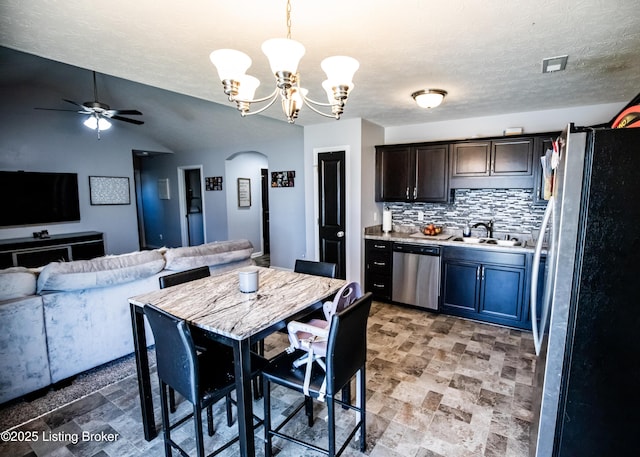 kitchen with sink, tasteful backsplash, pendant lighting, stainless steel appliances, and ceiling fan with notable chandelier