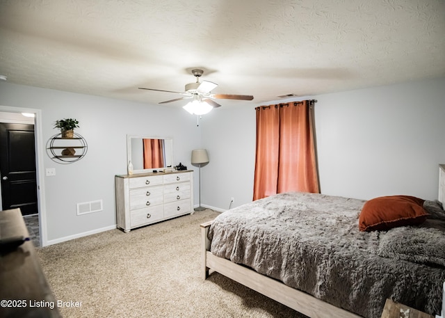 bedroom with ceiling fan, light carpet, and a textured ceiling