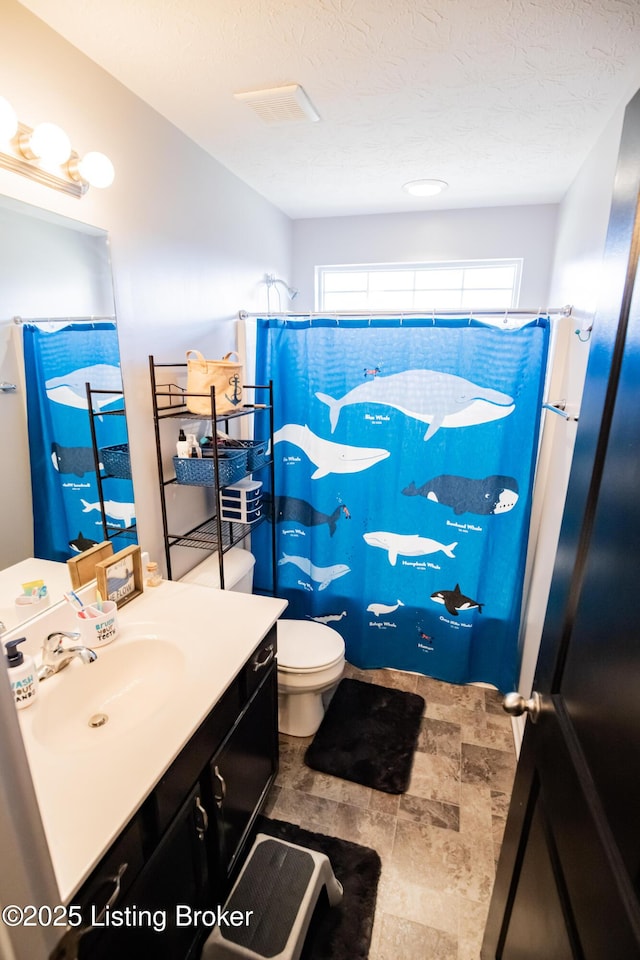 bathroom featuring walk in shower, vanity, toilet, and a textured ceiling