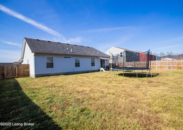 rear view of property featuring a trampoline and a yard