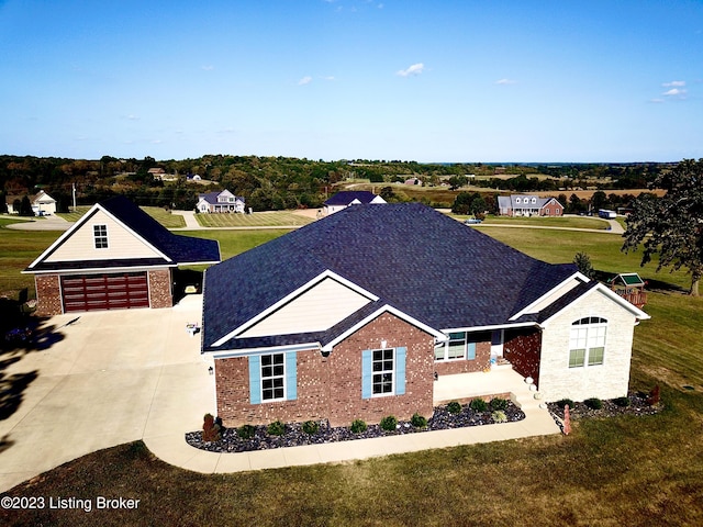 view of front of property featuring brick siding, driveway, a shingled roof, and a front yard