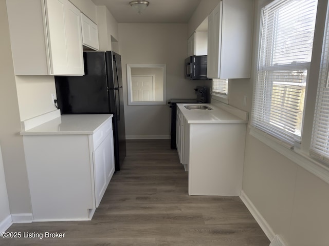 kitchen featuring hardwood / wood-style floors, black appliances, and white cabinets