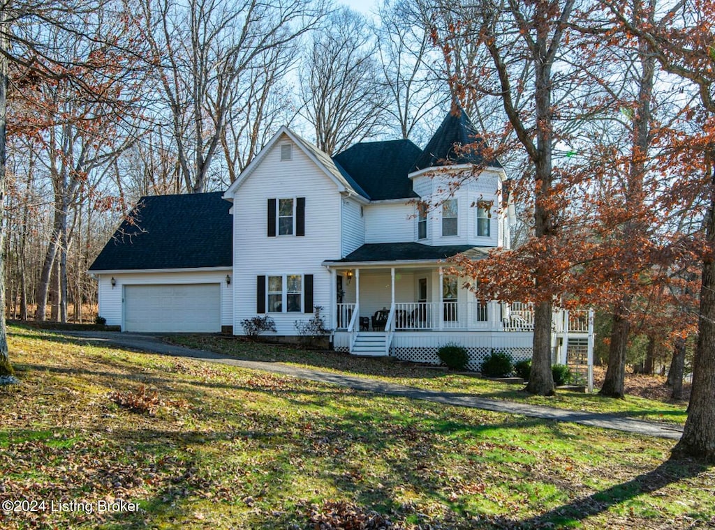 view of front of property with a garage, covered porch, and a front lawn