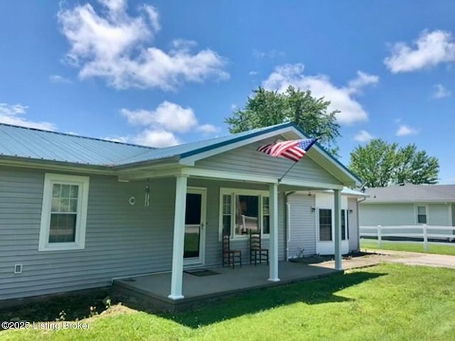 back of property with a yard and covered porch