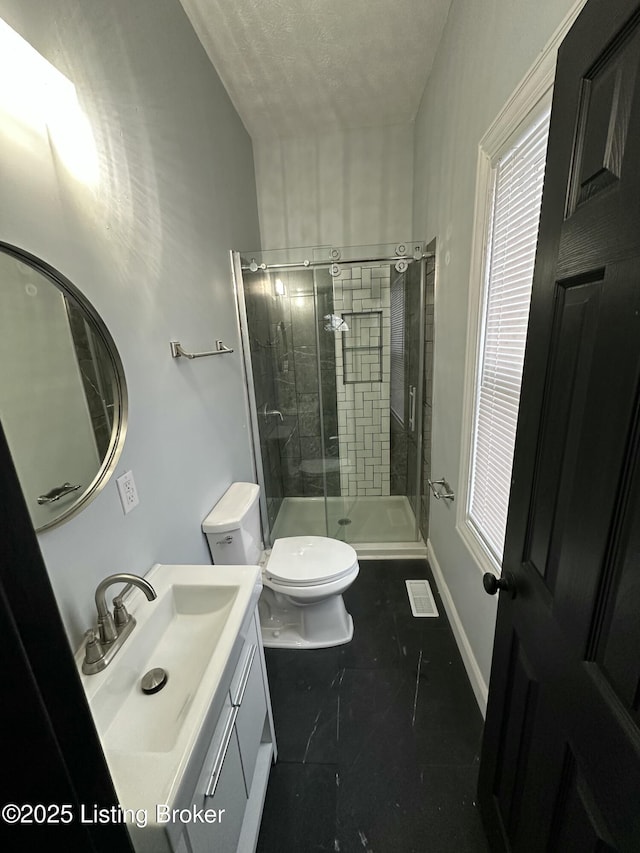 bathroom featuring baseboards, a shower stall, toilet, and vanity