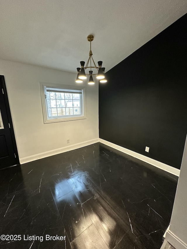 unfurnished dining area with a textured ceiling, an inviting chandelier, and baseboards