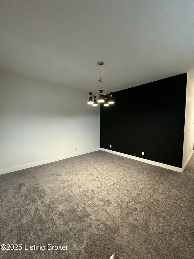 spare room with carpet floors, baseboards, and an inviting chandelier