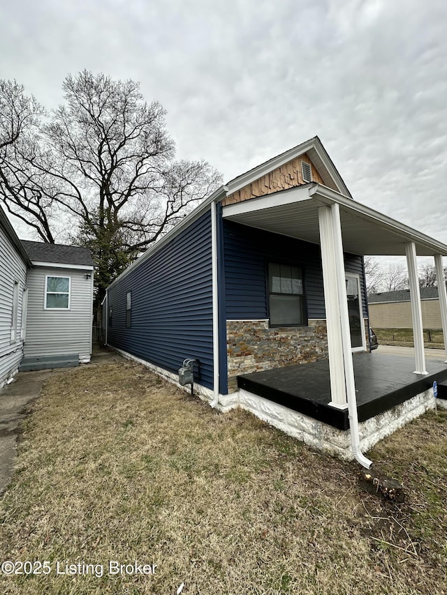 view of side of property with stone siding and a yard