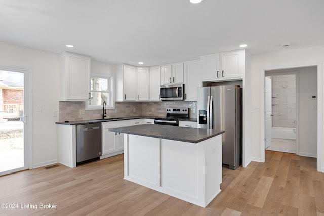 kitchen featuring sink, light hardwood / wood-style flooring, appliances with stainless steel finishes, white cabinetry, and a kitchen island