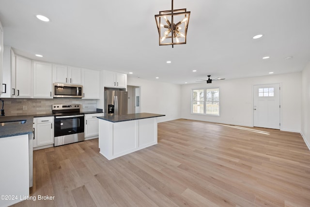 kitchen featuring decorative light fixtures, white cabinetry, sink, stainless steel appliances, and light hardwood / wood-style flooring