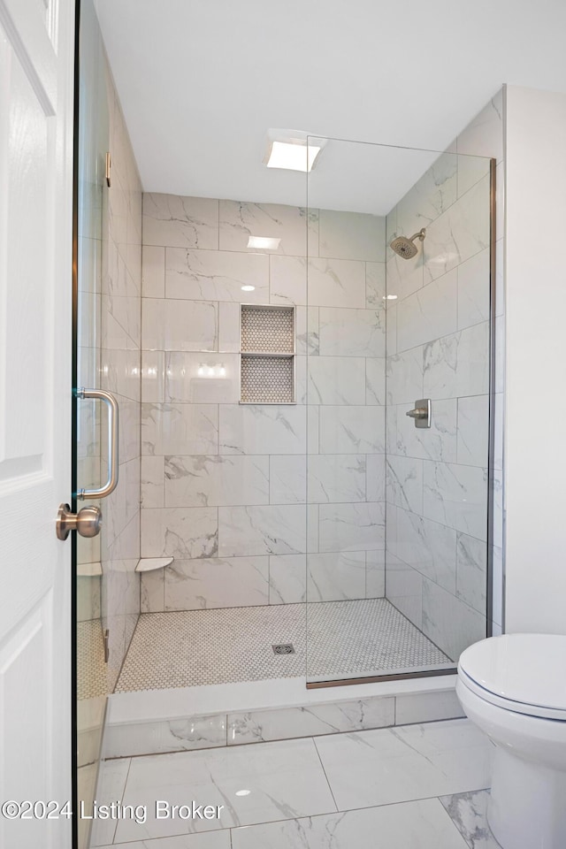 bathroom featuring a shower with shower door and toilet