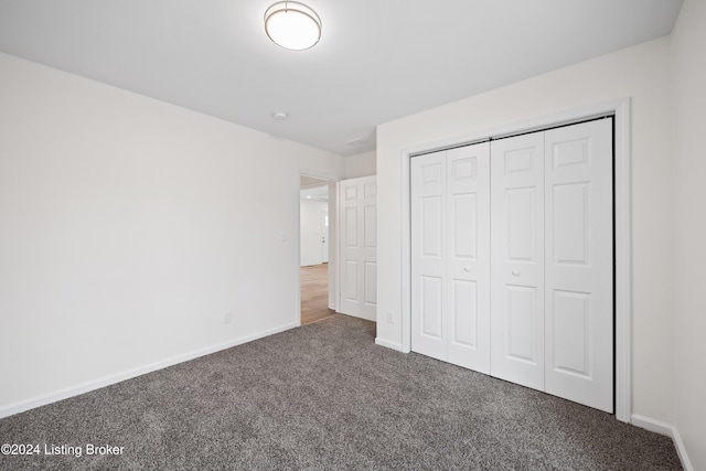 unfurnished bedroom with dark carpet and a closet