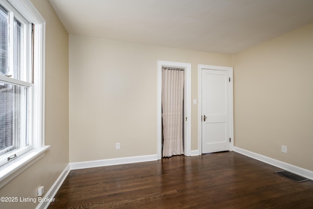 empty room with dark hardwood / wood-style flooring and a wealth of natural light