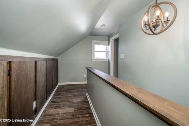 corridor with vaulted ceiling, dark wood-type flooring, and a chandelier