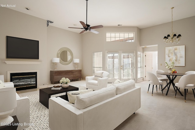 living room featuring light carpet, a towering ceiling, and ceiling fan with notable chandelier