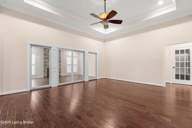 spare room featuring dark hardwood / wood-style flooring, ceiling fan, crown molding, and a raised ceiling