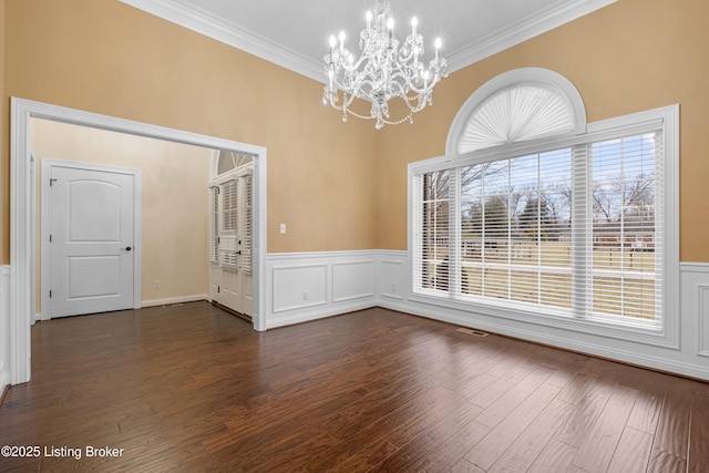 empty room featuring an inviting chandelier, dark hardwood / wood-style flooring, and ornamental molding