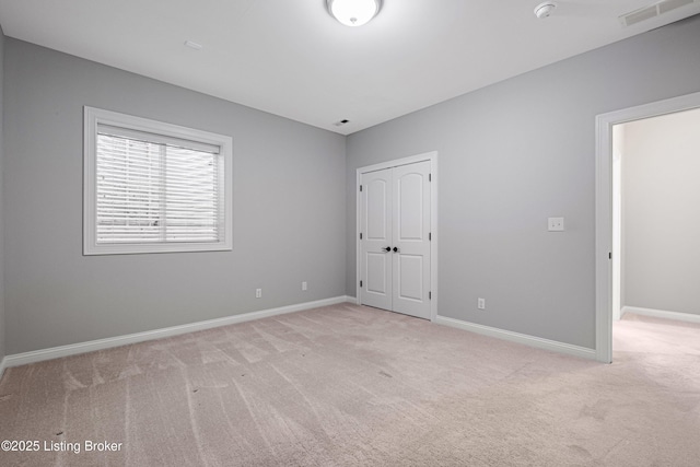 unfurnished bedroom featuring a closet and light colored carpet