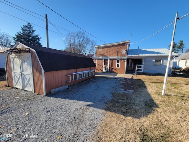 back of property featuring a yard and a storage unit