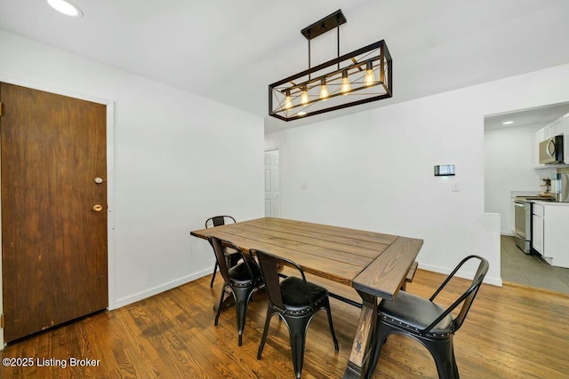 dining room featuring recessed lighting, wood finished floors, and baseboards