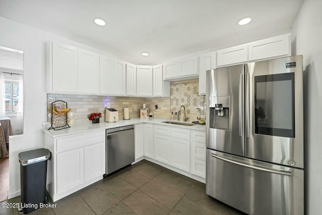 kitchen with appliances with stainless steel finishes, white cabinetry, a sink, and decorative backsplash