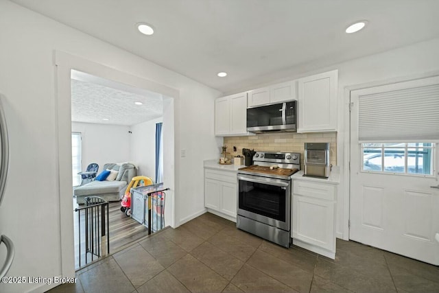 kitchen with stainless steel appliances, backsplash, light countertops, and white cabinets