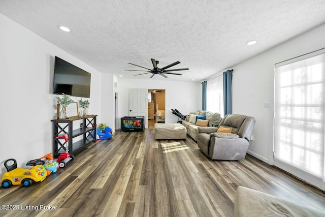 living area with recessed lighting, a textured ceiling, baseboards, and wood finished floors