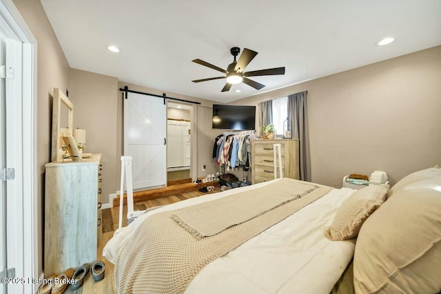 bedroom with a barn door, ceiling fan, wood finished floors, and recessed lighting