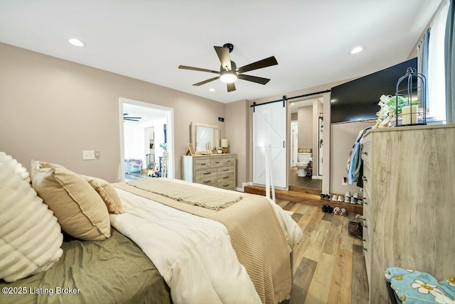 bedroom featuring recessed lighting, a barn door, light wood-style floors, a ceiling fan, and ensuite bath