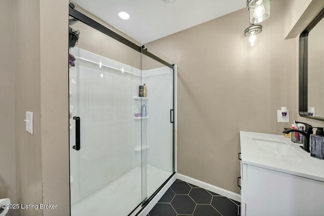 full bath with baseboards, vanity, a shower stall, and tile patterned floors