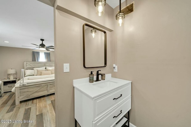 bathroom with ceiling fan, wood finished floors, vanity, and ensuite bathroom